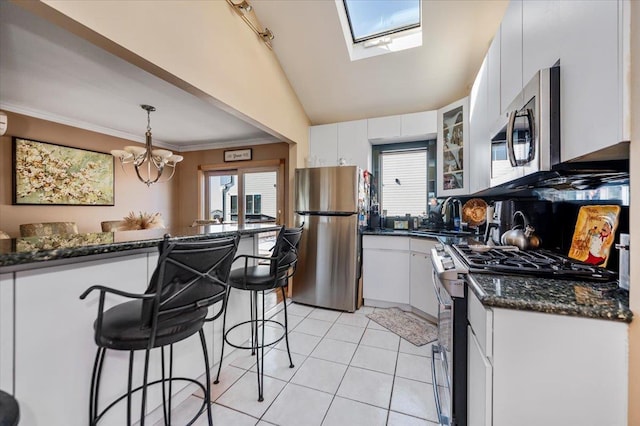 22 Cheshire Rd, Inwood, NY 11096 - kitchen with stainless steel appliances, a sink, a kitchen breakfast bar, white cabinetry, and vaulted ceiling