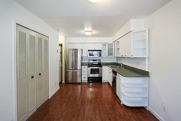 223 Springmeadow Dr Unit E, Holbrook, NY 11741 - kitchen with stainless steel appliances, open shelves, a sink, dark countertops, and dark wood finished floors