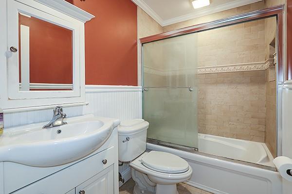 223 Springmeadow Dr Unit E, Holbrook, NY 11741 - bathroom with ornamental molding, vanity, toilet, shower / bath combination with glass door, and wainscoting