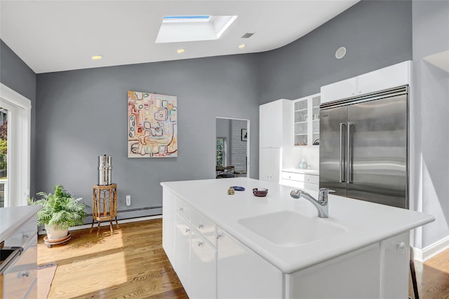 62 Woodhail St, Lido Beach, NY 11561 - kitchen with a sink, built in fridge, a skylight, white cabinetry, and high vaulted ceiling