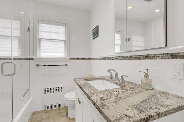 62 Woodhail St, Lido Beach, NY 11561 - bathroom with radiator, toilet, vanity, tile walls, and bath / shower combo with glass door