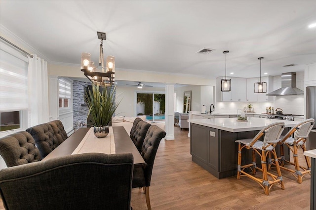 105 Shoreham Way, Merrick, NY 11566 - dining room with light wood finished floors, a chandelier, ornate columns, ceiling fan, and ornamental molding