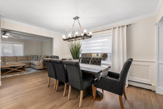 105 Shoreham Way, Merrick, NY 11566 - dining room featuring a baseboard radiator, healthy amount of natural light, a chandelier, ornamental molding, and light wood finished floors