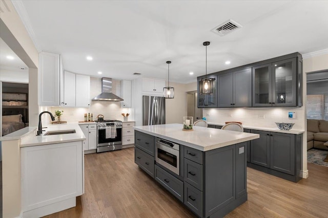 105 Shoreham Way, Merrick, NY 11566 - kitchen featuring appliances with stainless steel finishes, wall chimney exhaust hood, a sink, gray cabinets, and tasteful backsplash