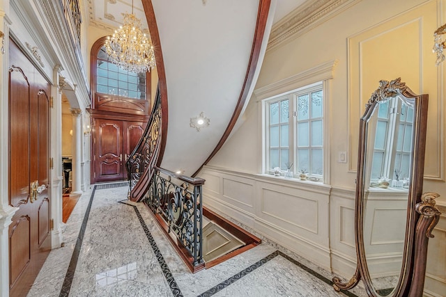 16136 90th St, Howard Beach, NY 11414 - entrance foyer featuring inlaid floor details, a chandelier, ornamental molding, a decorative wall, and wainscoting