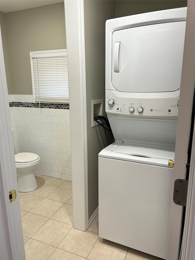 11 Fox Holw, Hillburn, NY 10931 - laundry area with estacked washer and dryer, light tile patterned floors, tile walls, and a wainscoted wall