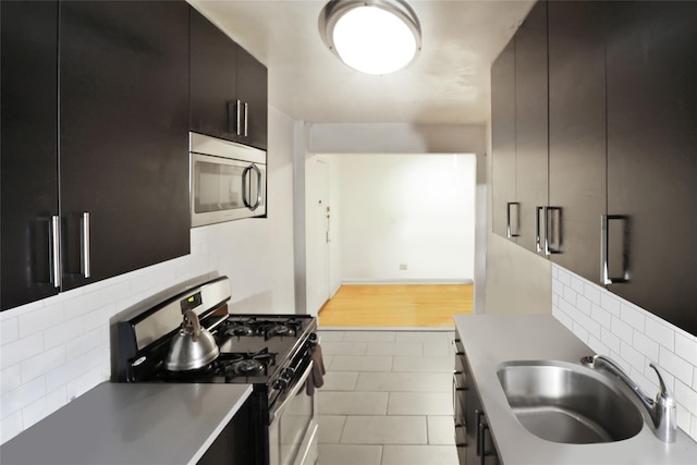 2105 Wallace Ave Unit 4A, Bronx, NY 10462 - kitchen featuring appliances with stainless steel finishes, tasteful backsplash, modern cabinets, dark cabinetry, and tile patterned floors