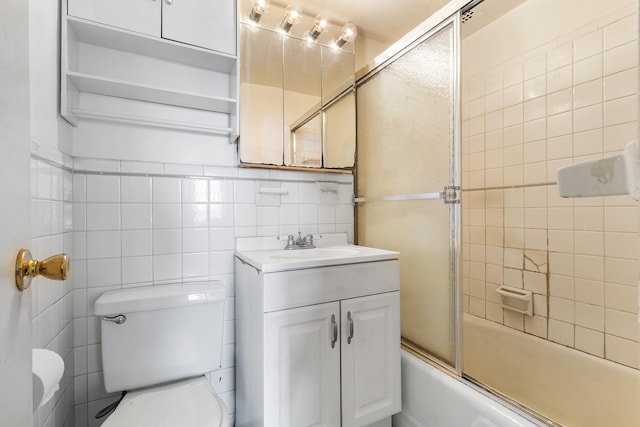 61-15 97th St Unit 8M, Rego Park, NY 11374 - bathroom featuring toilet, vanity, shower / bath combination with glass door, and tile walls