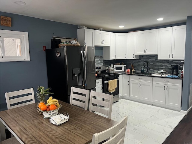 1251 Udall Rd, Bay Shore, NY 11706 - kitchen with appliances with stainless steel finishes, a sink, light marble finish flooring, dark countertops, and white cabinets