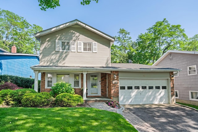 92 Radcliff Ave, Port Washington, NY 11050 - traditional-style house featuring brick siding, a garage, asphalt driveway, a front lawn, and covered porch