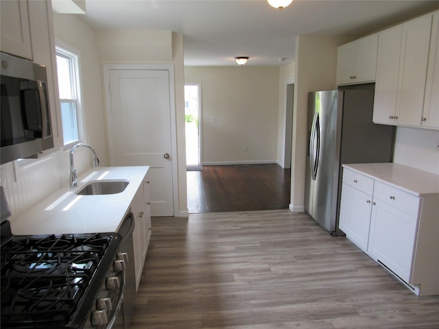506 Raynor Ave, Riverhead, NY 11901 - kitchen featuring stainless steel appliances, a sink, light countertops, light wood finished floors, and white cabinetry