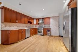 12-08 Robin Ln Unit 11-L, Bayside, NY 11360 - kitchen with stainless steel appliances, light countertops, light wood-style flooring, brown cabinets, and tasteful backsplash