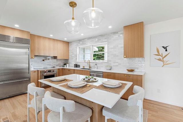 2000 Beebe Dr, Cutchogue, NY 11935 - kitchen with appliances with stainless steel finishes, decorative backsplash, a kitchen bar, light wood-style floors, and recessed lighting