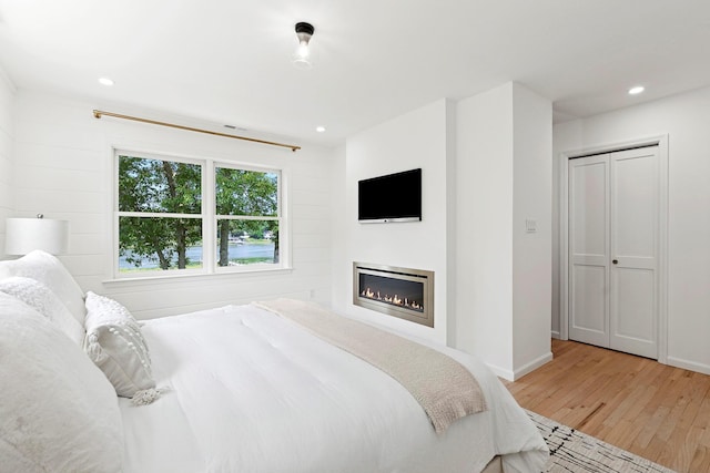 2000 Beebe Dr, Cutchogue, NY 11935 - bedroom featuring light wood-style floors, a glass covered fireplace, and recessed lighting