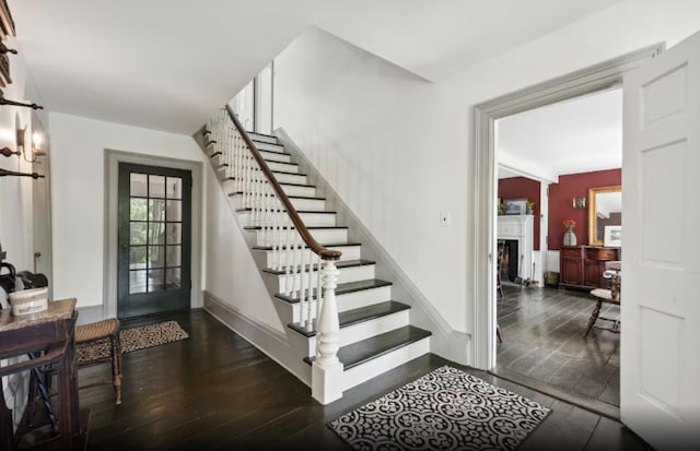 stairway featuring hardwood / wood-style flooring, a fireplace, and baseboards