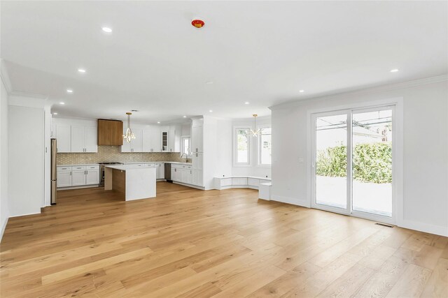 9 Vista Ln, Levittown, NY 11756 - unfurnished living room with a chandelier, crown molding, recessed lighting, light wood-style floors, and a sink