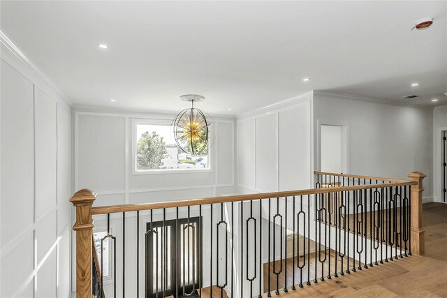 9 Vista Ln, Levittown, NY 11756 - hall featuring a decorative wall, a chandelier, an upstairs landing, wood finished floors, and crown molding