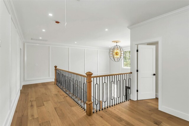 9 Vista Ln, Levittown, NY 11756 - hall with ornamental molding, wood finished floors, a decorative wall, a chandelier, and an upstairs landing