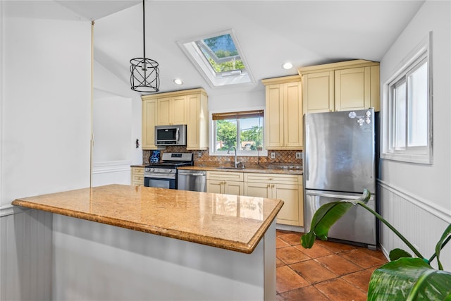 402 Chelsea Ave, West Babylon, NY 11704 - kitchen featuring appliances with stainless steel finishes, cream cabinetry, a sink, a skylight, and vaulted ceiling