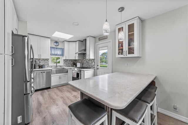 226 Mile Square Rd, Yonkers, NY 10701 - kitchen featuring stainless steel appliances, a peninsula, a kitchen bar, light wood-style floors, and a sink