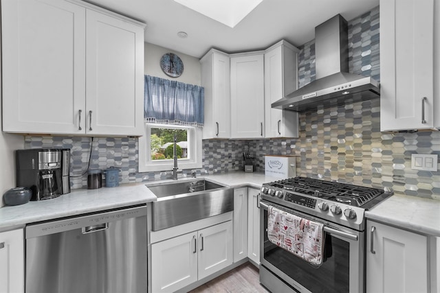 226 Mile Square Rd, Yonkers, NY 10701 - kitchen featuring appliances with stainless steel finishes, wall chimney exhaust hood, a sink, tasteful backsplash, and white cabinetry