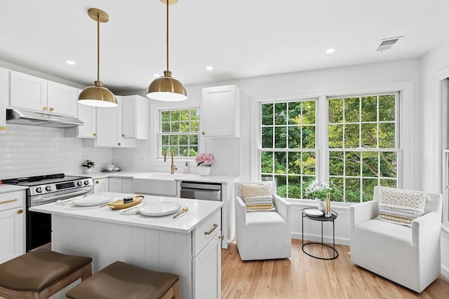 2850 Reeve Rd, Mattituck, NY 11952 - kitchen featuring stainless steel appliances, under cabinet range hood, light countertops, white cabinets, and decorative backsplash