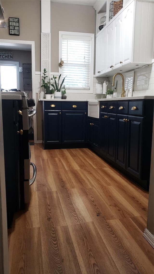 1026 Logan Ave, Bronx, NY 10465 - kitchen featuring white cabinetry, light countertops, light wood-style flooring, blue cabinetry, and wainscoting