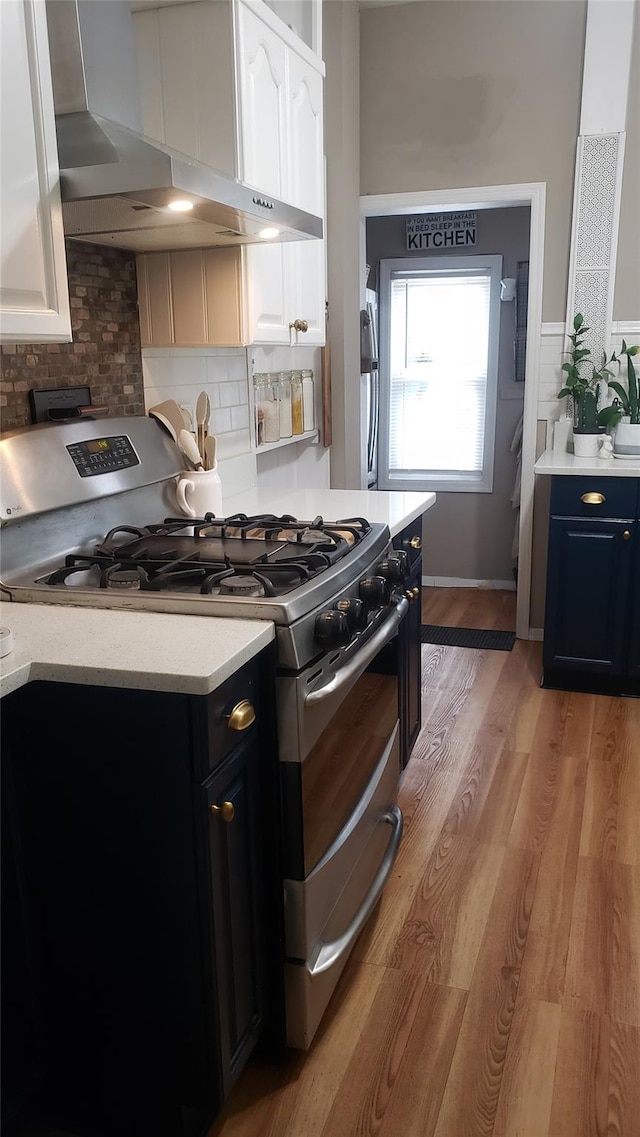 1026 Logan Ave, Bronx, NY 10465 - kitchen featuring stainless steel gas range, wall chimney range hood, light countertops, and white cabinetry