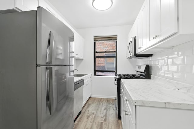 312 Main St Unit 4F, White Plains, NY 10601 - kitchen with stainless steel appliances, white cabinetry, light countertops, light wood-style floors, and backsplash
