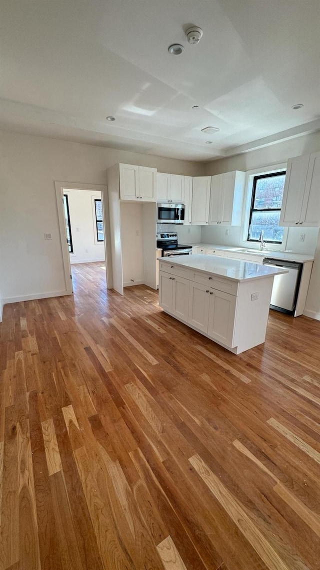 31 Roosevelt Pl, Brooklyn, NY 11233 - kitchen featuring stainless steel appliances, light wood finished floors, white cabinets, and a kitchen island