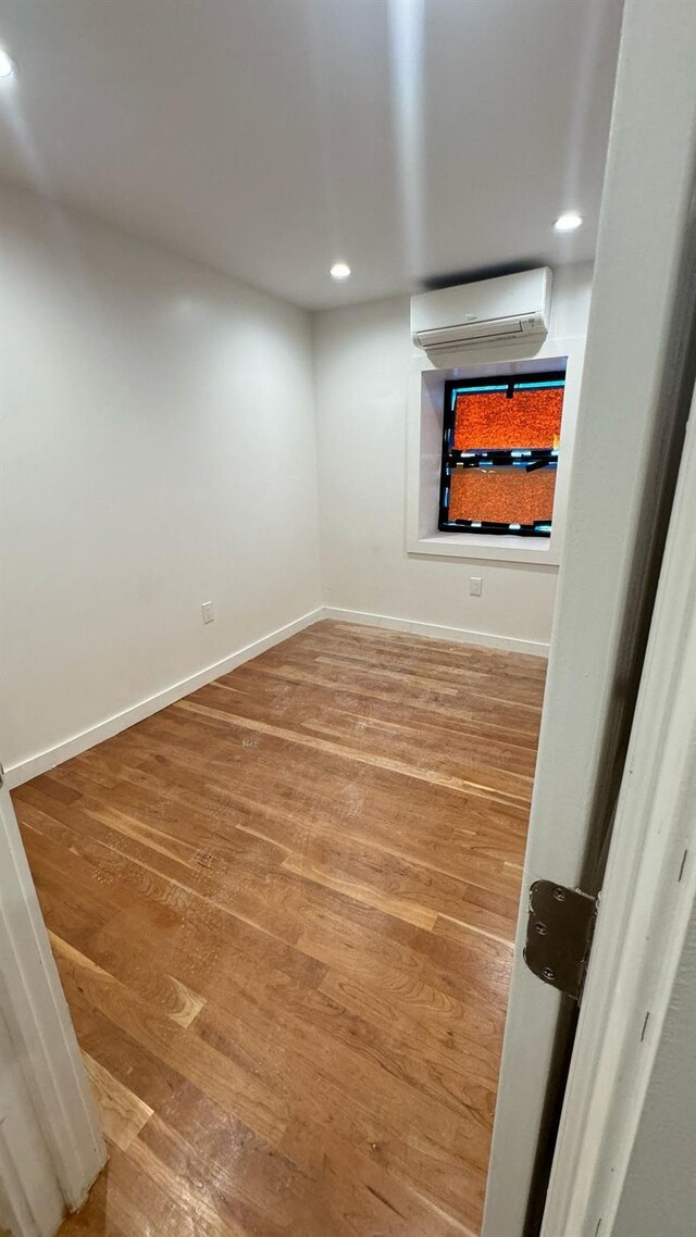 31 Roosevelt Pl, Brooklyn, NY 11233 - empty room with a wall unit AC, wood finished floors, and recessed lighting