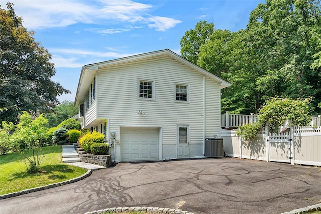 154 Meadow Lark Rd, Montgomery, NY 12549 - view of side of home featuring central AC unit, an attached garage, asphalt driveway, and a gate
