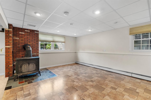 154 Meadow Lark Rd, Montgomery, NY 12549 - unfurnished living room featuring a baseboard heating unit, a wood stove, a drop ceiling, stone finish flooring, and baseboards