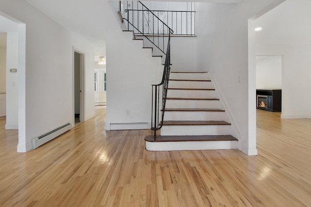 16 Sampson Ave, Islandia, NY 11749 - stairway with baseboard heating, wood finished floors, a glass covered fireplace, and baseboards