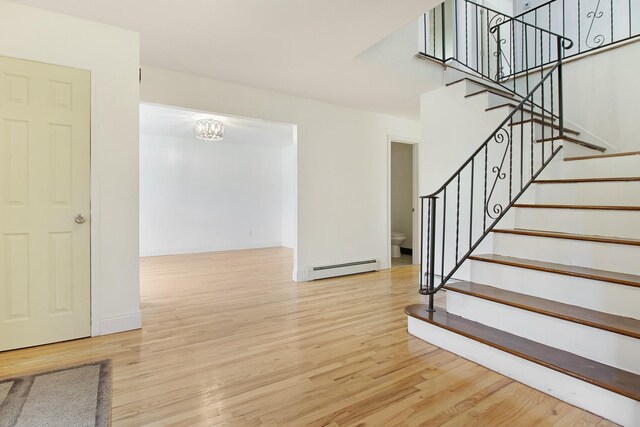 16 Sampson Ave, Islandia, NY 11749 - stairs featuring baseboard heating, wood finished floors, baseboards, and a chandelier