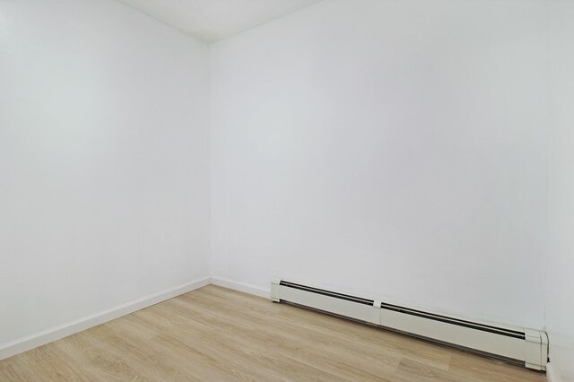 16 Sampson Ave, Islandia, NY 11749 - empty room with baseboard heating, light wood-style flooring, and baseboards
