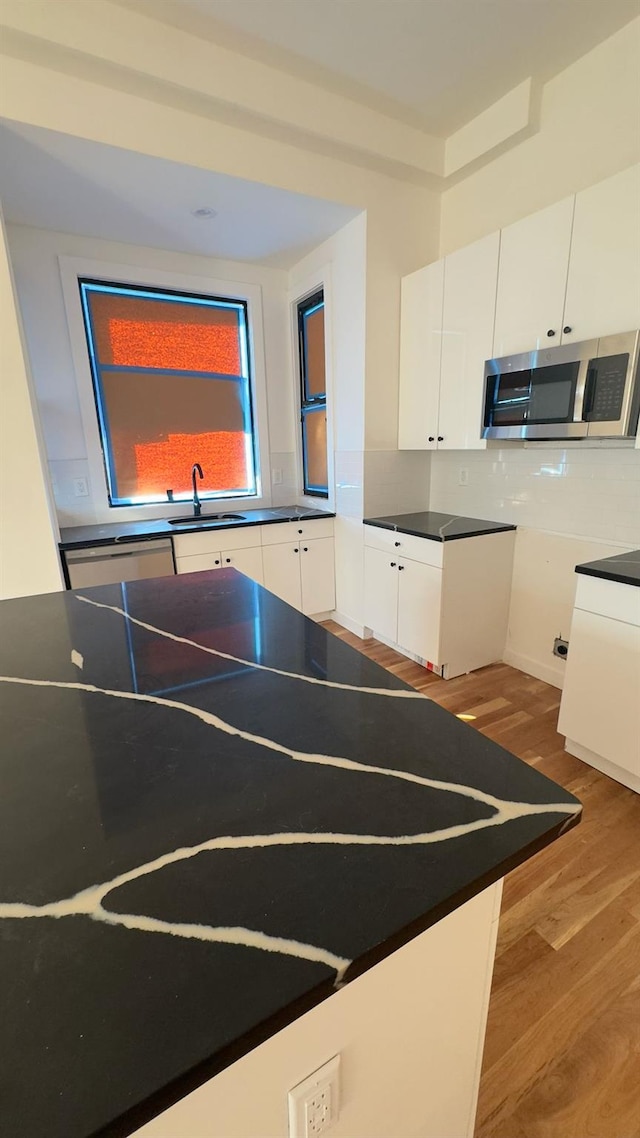 32 Radde Pl, Brooklyn, NY 11233 - kitchen with stainless steel microwave, dark countertops, wood finished floors, and white cabinets