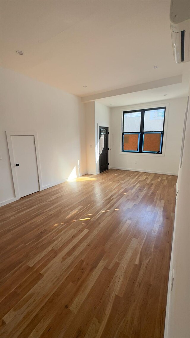 32 Radde Pl, Brooklyn, NY 11233 - empty room with wood finished floors and a wall mounted AC