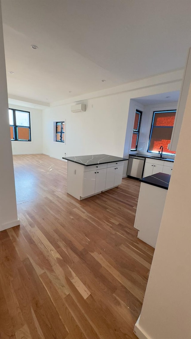 32 Radde Pl, Brooklyn, NY 11233 - kitchen with white cabinets, light wood finished floors, dark countertops, and a wall unit AC