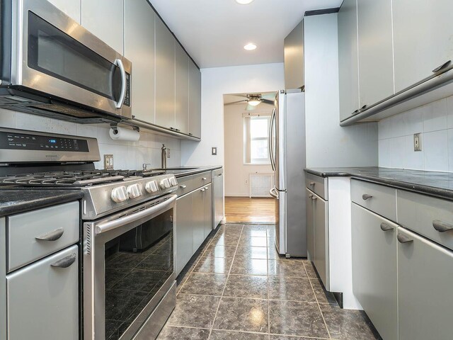 32 Pearsall Ave Unit 3A, Glen Cove, NY 11542 - kitchen with appliances with stainless steel finishes, dark countertops, decorative backsplash, ceiling fan, and a sink