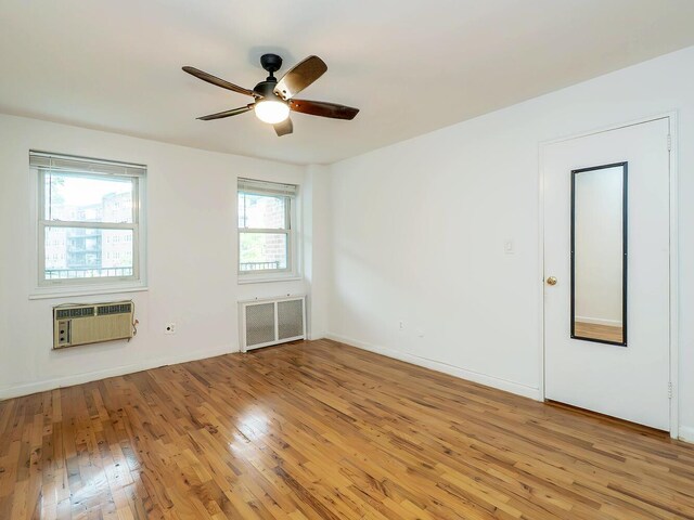 32 Pearsall Ave Unit 3A, Glen Cove, NY 11542 - empty room with radiator heating unit, light wood-style floors, a ceiling fan, a wall unit AC, and baseboards