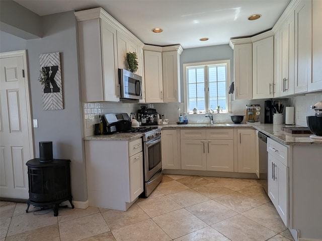 3403 Bay Front Dr, Baldwin, NY 11510 - kitchen featuring appliances with stainless steel finishes, tasteful backsplash, a sink, light stone countertops, and recessed lighting