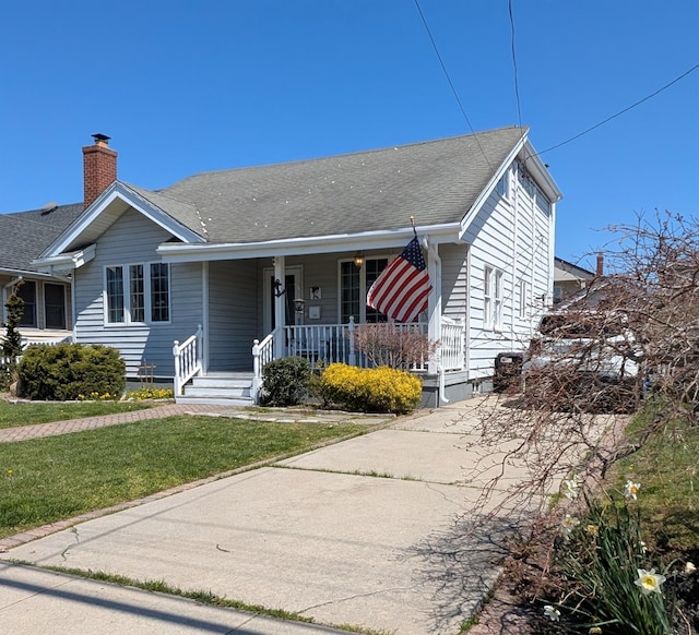 3403 Bay Front Dr, Baldwin, NY 11510 - view of front of property with covered porch, a front lawn, concrete driveway, and roof with shingles