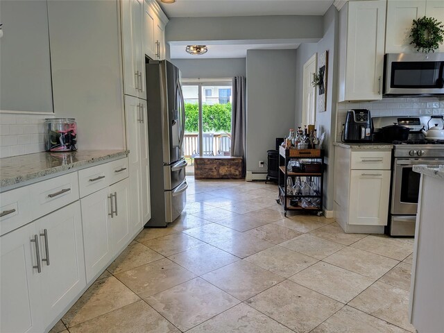 3403 Bay Front Dr, Baldwin, NY 11510 - kitchen with stainless steel appliances, tasteful backsplash, white cabinetry, and light stone countertops