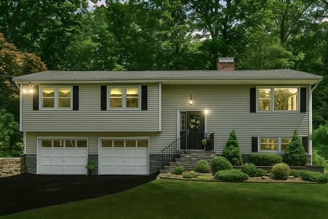 69 Clove Brook Dr, Cold Spring, NY 10516 - raised ranch with asphalt driveway, a garage, a chimney, a front yard, and view of wooded area