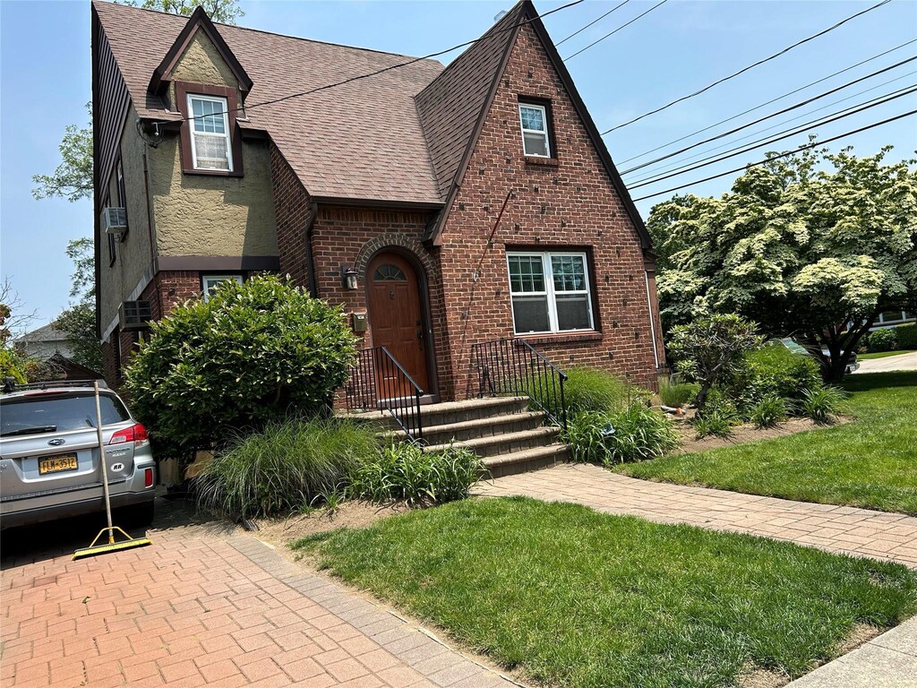 9 Troy Pl, Merrick, NY 11566 - english style home with roof with shingles, brick siding, and a front lawn