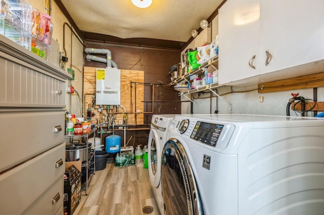 203 E Shore Rd, Lindenhurst, NY 11757 - washroom featuring washing machine and clothes dryer, water heater, light wood-style flooring, and cabinet space