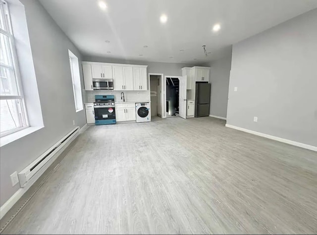 348 Legion St, Brooklyn, NY 11212 - unfurnished living room with washer / dryer, a baseboard heating unit, baseboards, a sink, and light wood-type flooring
