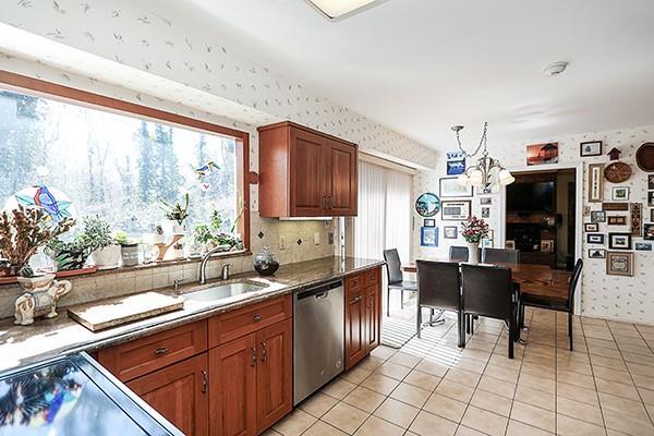 12 Rustic Gate Ln, Dix Hills, NY 11746 - kitchen with stainless steel dishwasher, wallpapered walls, a sink, a chandelier, and light tile patterned floors