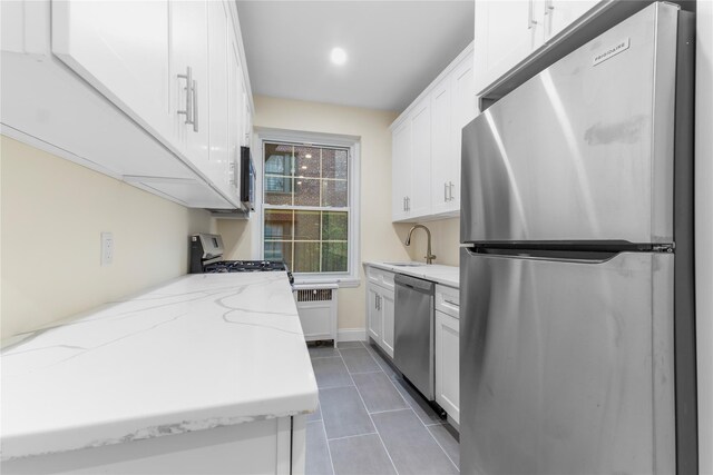 11007 73rd Rd Unit 4D, Forest Hills, NY 11375 - kitchen with appliances with stainless steel finishes, white cabinetry, dark tile patterned flooring, a sink, and radiator